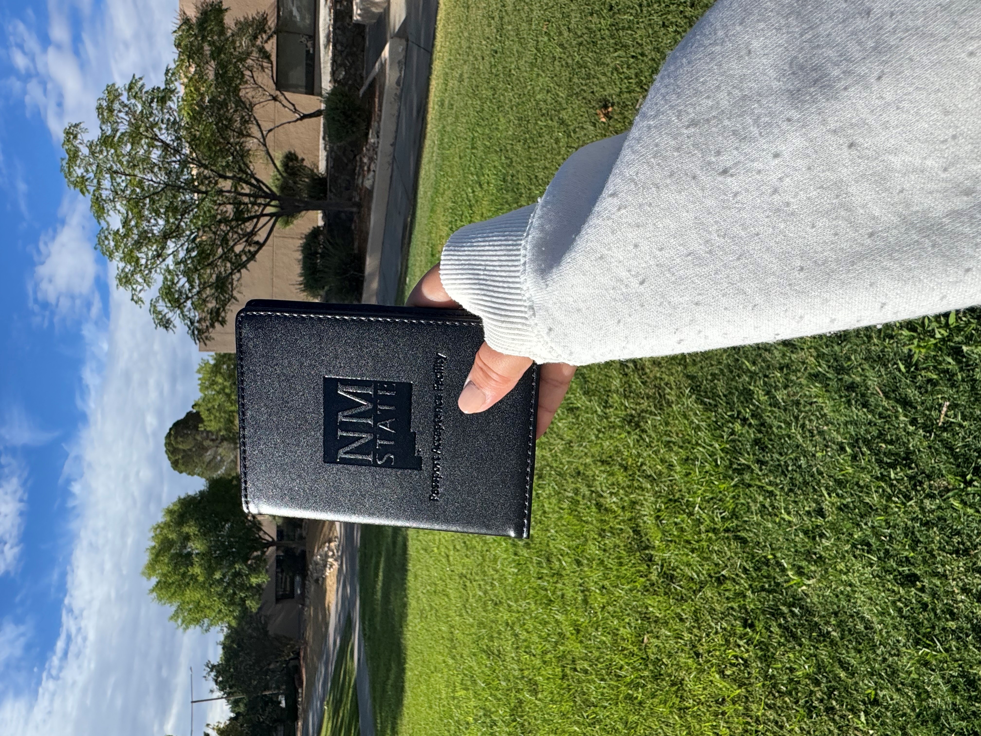 Image of a black leather passport sleeve with an NMSU logo on the cover.